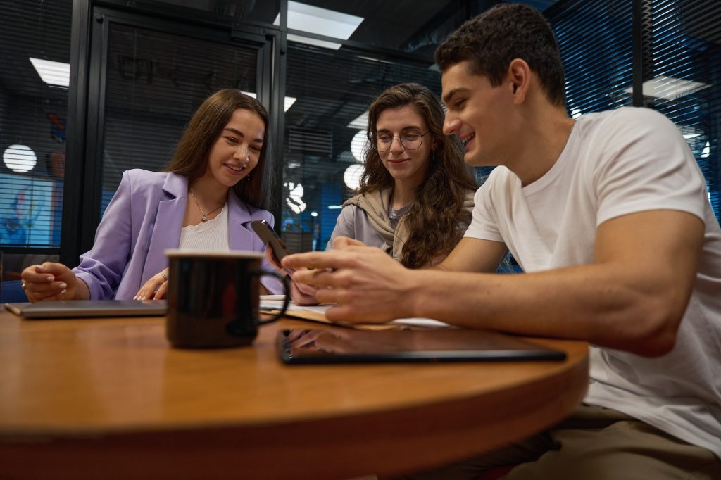 Trainee guy showing photo on phone to ladies during break